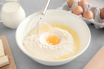 Bowl with whisk, flour and yolk on kitchen table. Bakery workshop