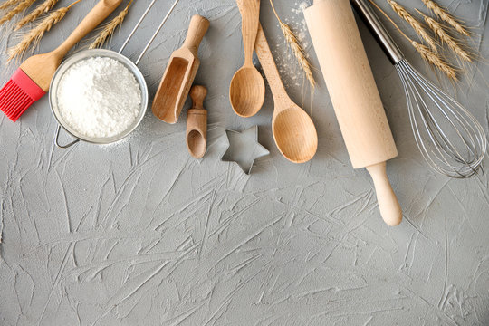 Flat lay composition with kitchen utensils and flour on grey background. Bakery workshop