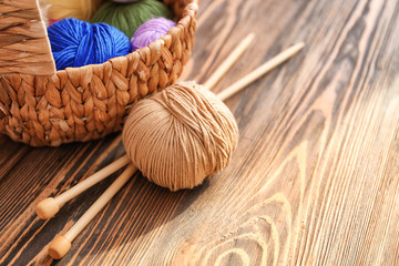 Wicker basket with knitting yarn and needles on table