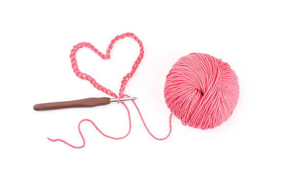 Ball of knitting yarn with crochet hook on white background