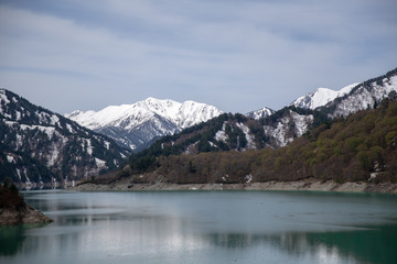 Fototapeta na wymiar Scenery of lake and mountains from Kurobe Dam in Tateyama Kurobe Alpine Route, Japan