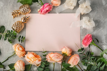 Composition with beautiful flowers and blank card on grey background