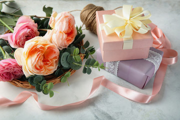 Composition with beautiful flowers and gift boxes on light background