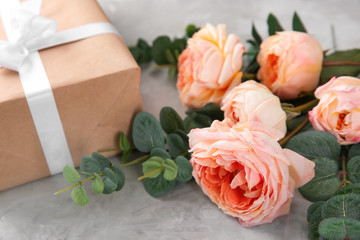 Beautiful flowers and gift box on grey background, closeup