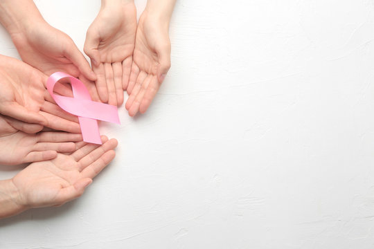 Female hands holding pink ribbon on white background. Breast cancer awareness concept