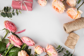 Frame made of beautiful roses, twine and gift boxes on light background