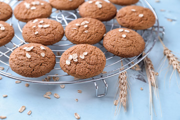 Cooling rack with delicious oatmeal cookies on color background