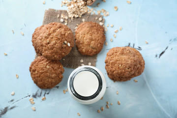 Delicious oatmeal cookies and bottle of milk on color background
