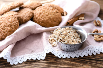 Raw oatmeal and delicious cookies on wooden background