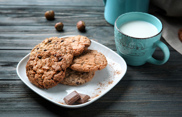 Plate with delicious oatmeal cookies and cup of milk on table