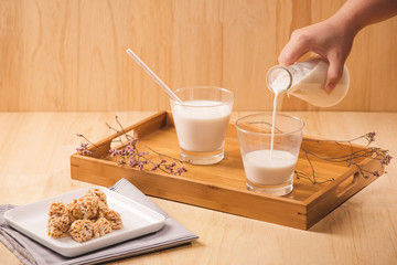 milk pour from bottle, almond candies on wooden background