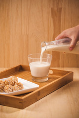 milk pour from bottle, almond candies on wooden background