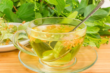 Linden tea in transparent glass cup with tea spoon closeup