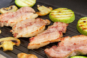 Grilled streaky bacon with vegetables and mushrooms at selective focus