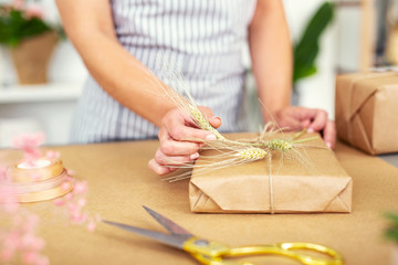 Handmade decoration. Nice young woman decorating a present while working in the gift shop