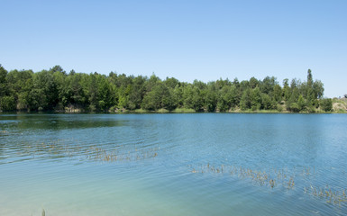 Landscape with clear lake and blue sky with trees on the horizon, Summer time and reflection in the water