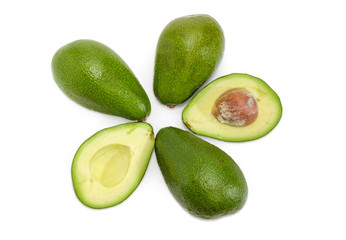 One green avocado cut in half and several whole avocados