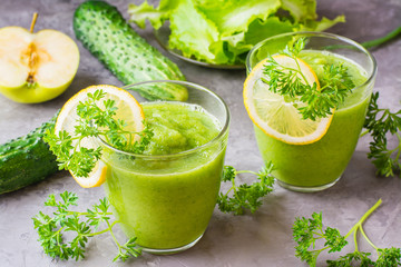 Refreshing smoothies from cucumber, green apple, fresh herbs and lemon juice in transparent glasses on the table. The concept of a healthy diet. Vegetarian menu