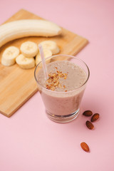 Banana smoothie with banana, milk, almonds in glass glasses on a white table, top view, horizontal, selective focus