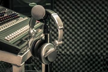 Close up instruments music background concept.Headphones hang  on microphone with sound mixer board in home recording studio.Free space for creative design text & wording mock up template wallpaper.