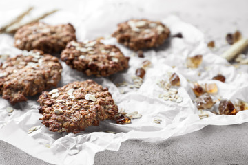 Parchment with delicious oatmeal cookies on light background