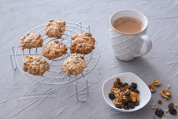 Cooling rack with oatmeal cookies and cup of coffee on textured background