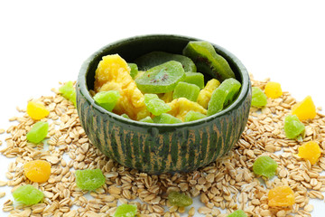 Bowl with oatmeal flakes and candied fruits on white background