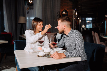young couple feeding each other in restaurant