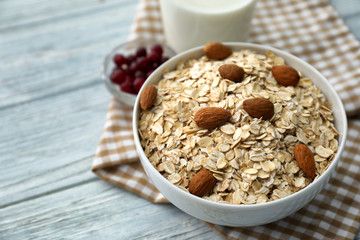 Bowl with raw oatmeal and nuts on wooden background
