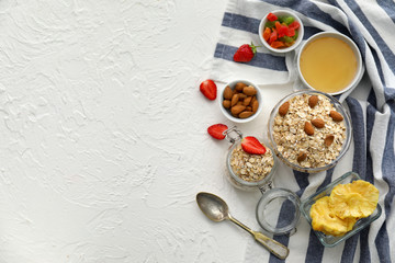 Composition with raw oatmeal, honey, nuts and strawberry on white textured background