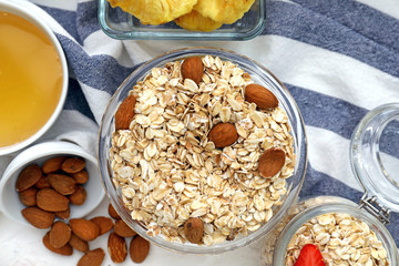 Bowl with raw oatmeal and nuts on table