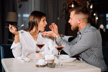 young couple feeding each other in restaurant