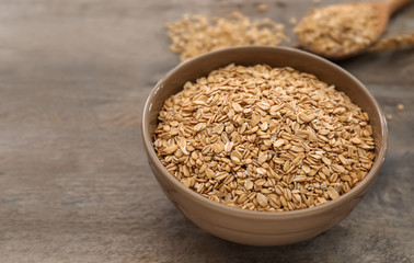Bowl with raw oatmeal on wooden background