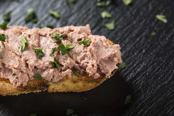 Liverwurst Sandwich with chopped parsley on a dark slate - close up view