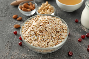 Bowl with oatmeal flakes on textured background