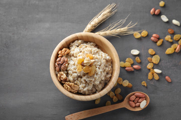 Obraz na płótnie Canvas Bowl with tasty oatmeal, raisins and nuts on grey background