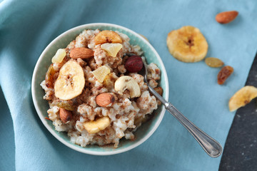 Bowl with tasty oatmeal and spoon on table