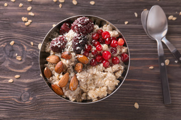 Tasty oatmeal with berries and nuts on wooden table