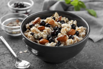 Bowl with tasty oatmeal, berries and nuts on grey textured background