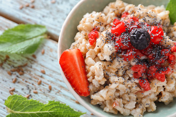 Bowl with tasty oatmeal and fresh berries on wooden table, closeup