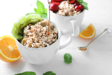 Cups with tasty oatmeal on light background