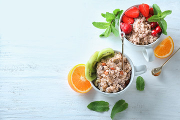 Cups with tasty oatmeal on light background