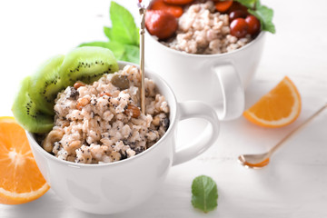 Cups with tasty oatmeal on light background