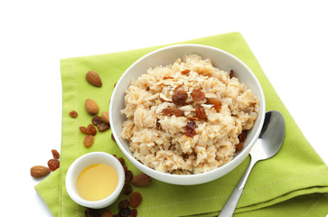 Tasty oatmeal with honey, nuts and raisins on white background