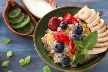 Tasty oatmeal with berries and fruits on wooden table
