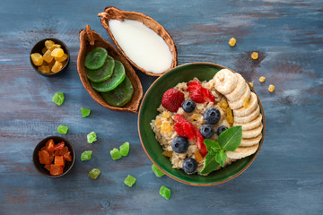 Composition with tasty oatmeal, berries and fruits on color wooden table