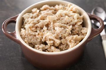 Tureen with tasty oatmeal on grey background