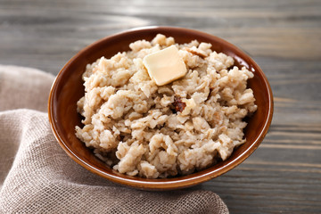 Bowl with tasty oatmeal on wooden table