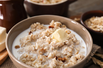 Tasty oatmeal with milk and butter in bowl on table, closeup