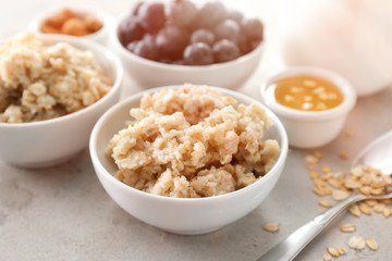 Bowl with tasty oatmeal on table